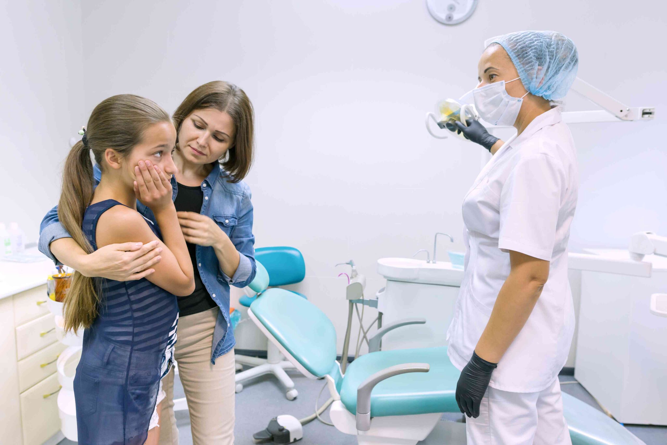 Child holding their jaw while speaking with a dentist about pain.