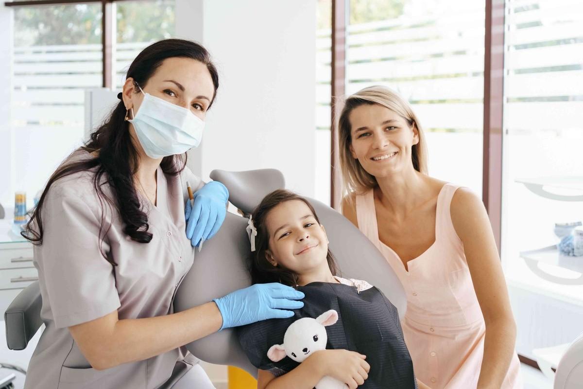 Pediatric dentist with a child and parent during a supportive dental visit