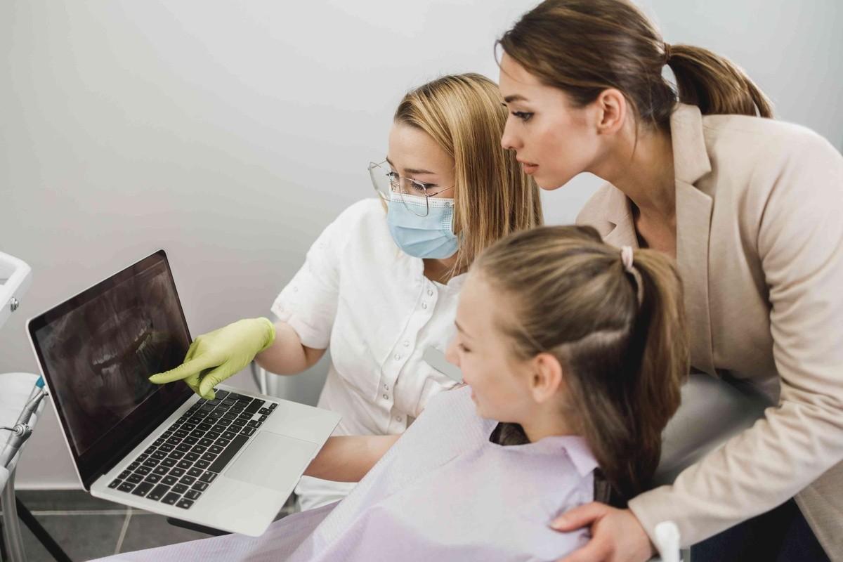 Dentist reviewing dental images with a child and parent during a pediatric dental consultation