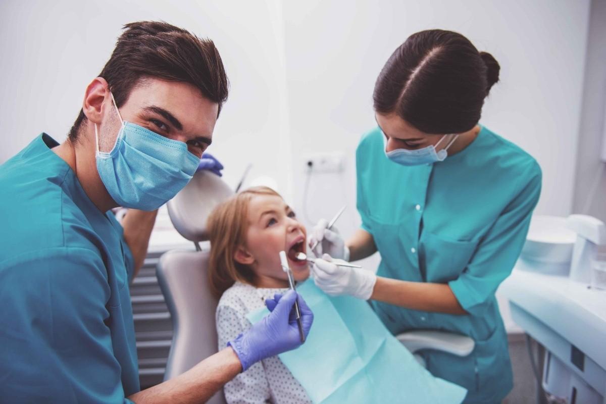 Pediatric dental team examining a child with urgent dental symptoms and tooth discomfort