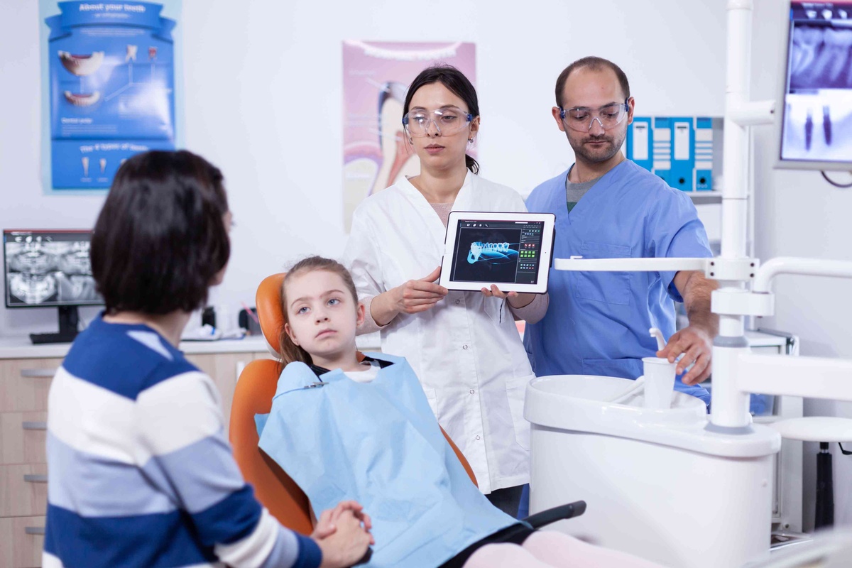Kids dentist explaining preventive dental care and healthy tooth development to parents.