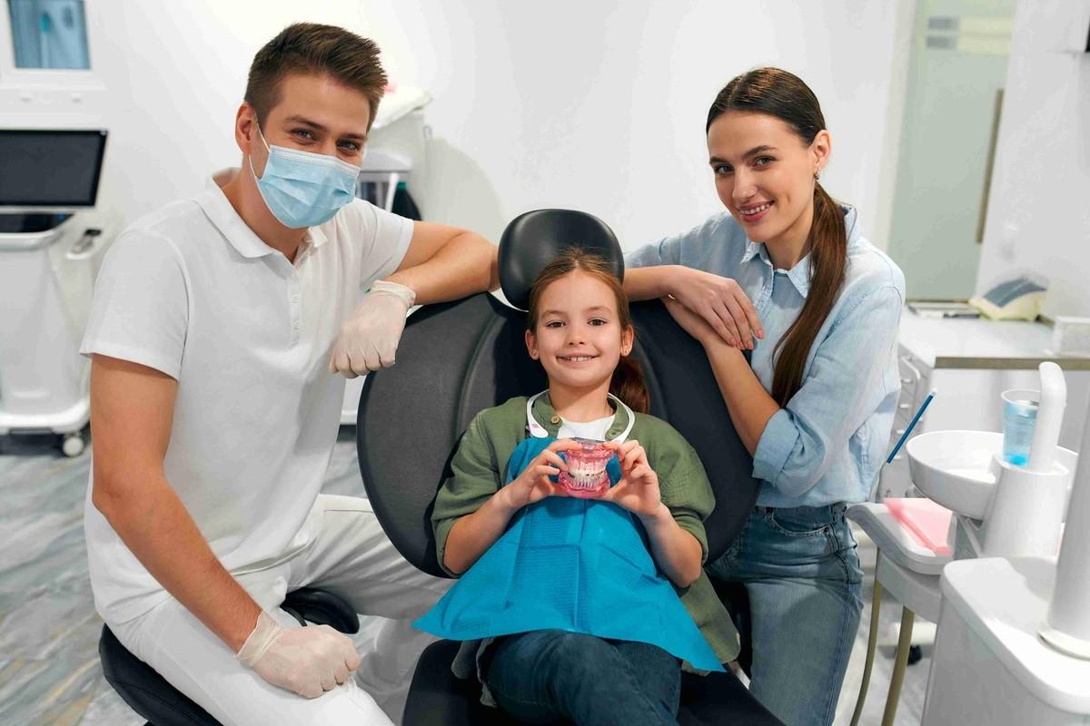 Child smiling with parents after a tooth restoration consultation at a dental office.